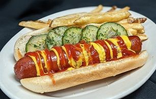 A hot dog with ketchup and mustard and french fries on a white plate.