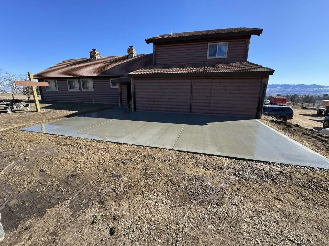 Woman in straw hat smiles, holding wine glass near a lake.