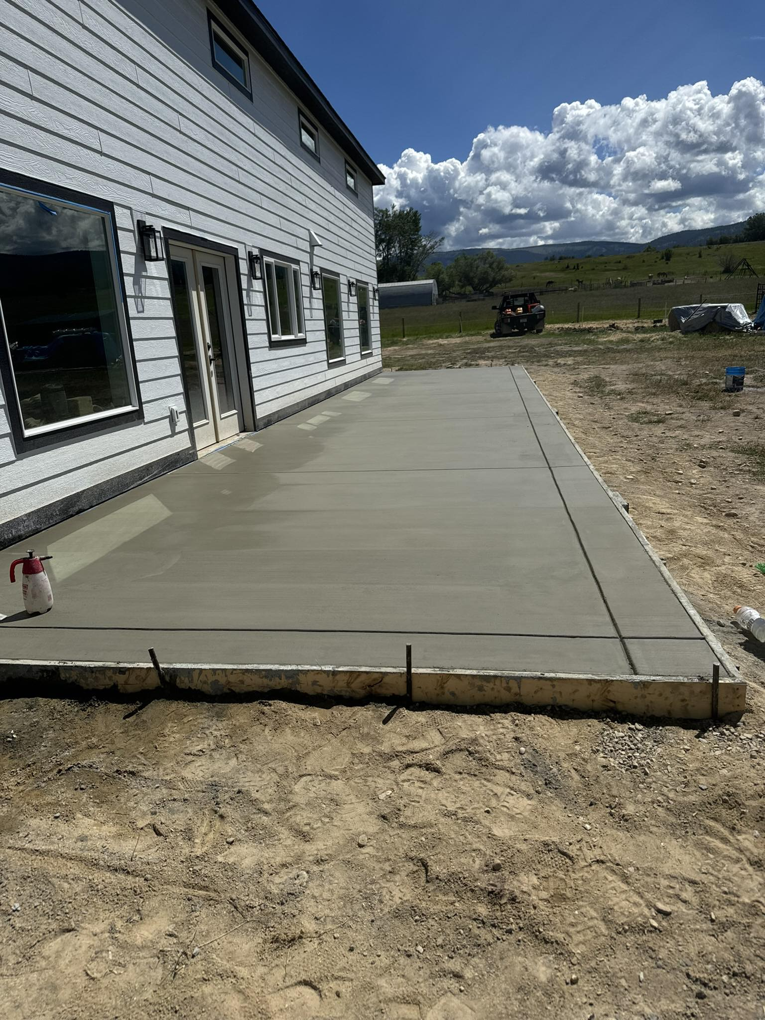 Woman in straw hat smiles, holding wine glass near a lake.
