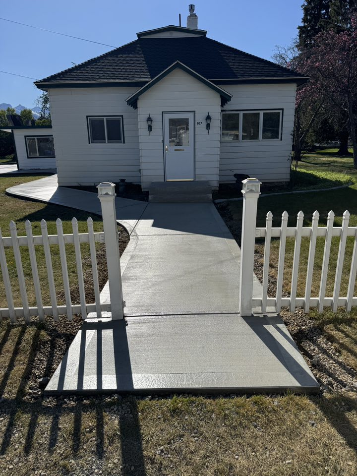 Woman in straw hat smiles, holding wine glass near a lake.