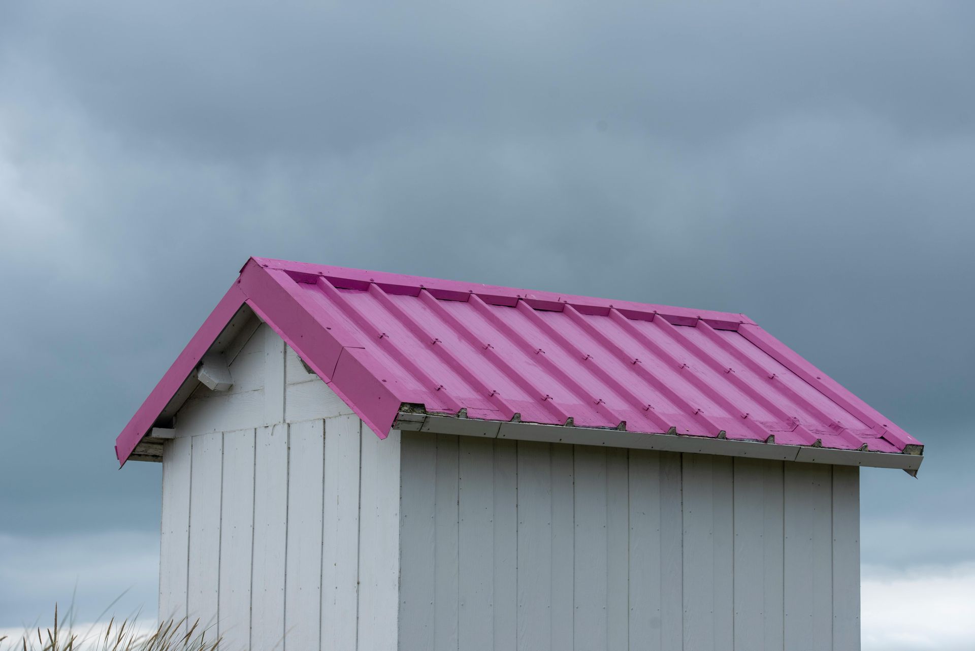 Woman in straw hat smiles, holding wine glass near a lake.