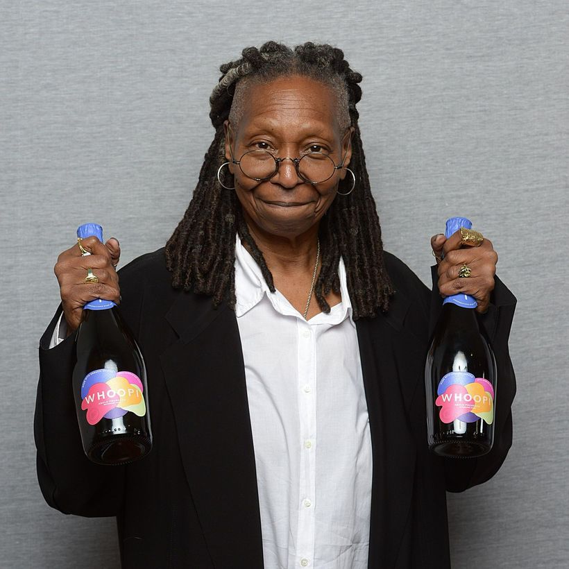 Whoopi Goldberg holding two bottles of Prosecco