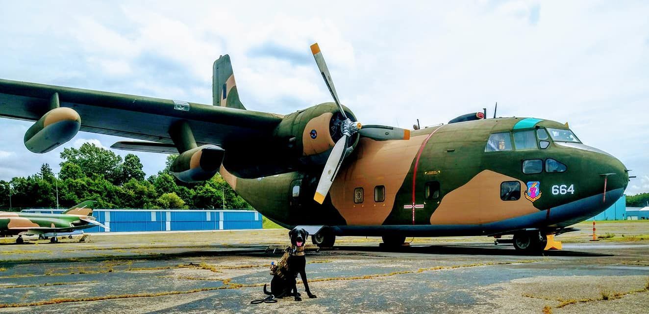 A man is standing in front of a large military plane.
