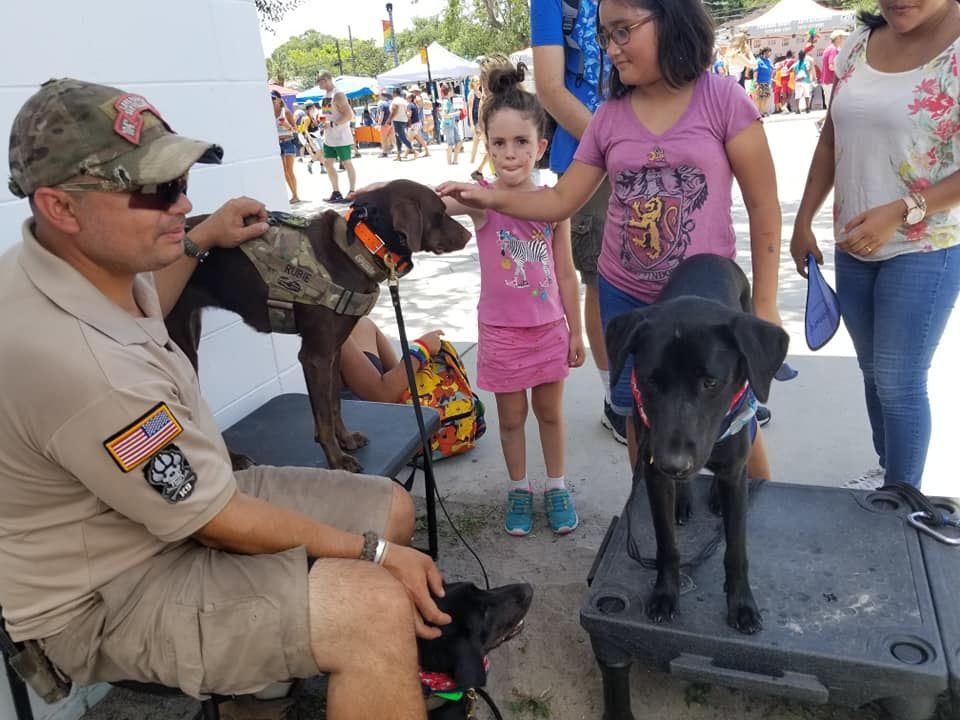 A man is sitting next to two dogs and a little girl