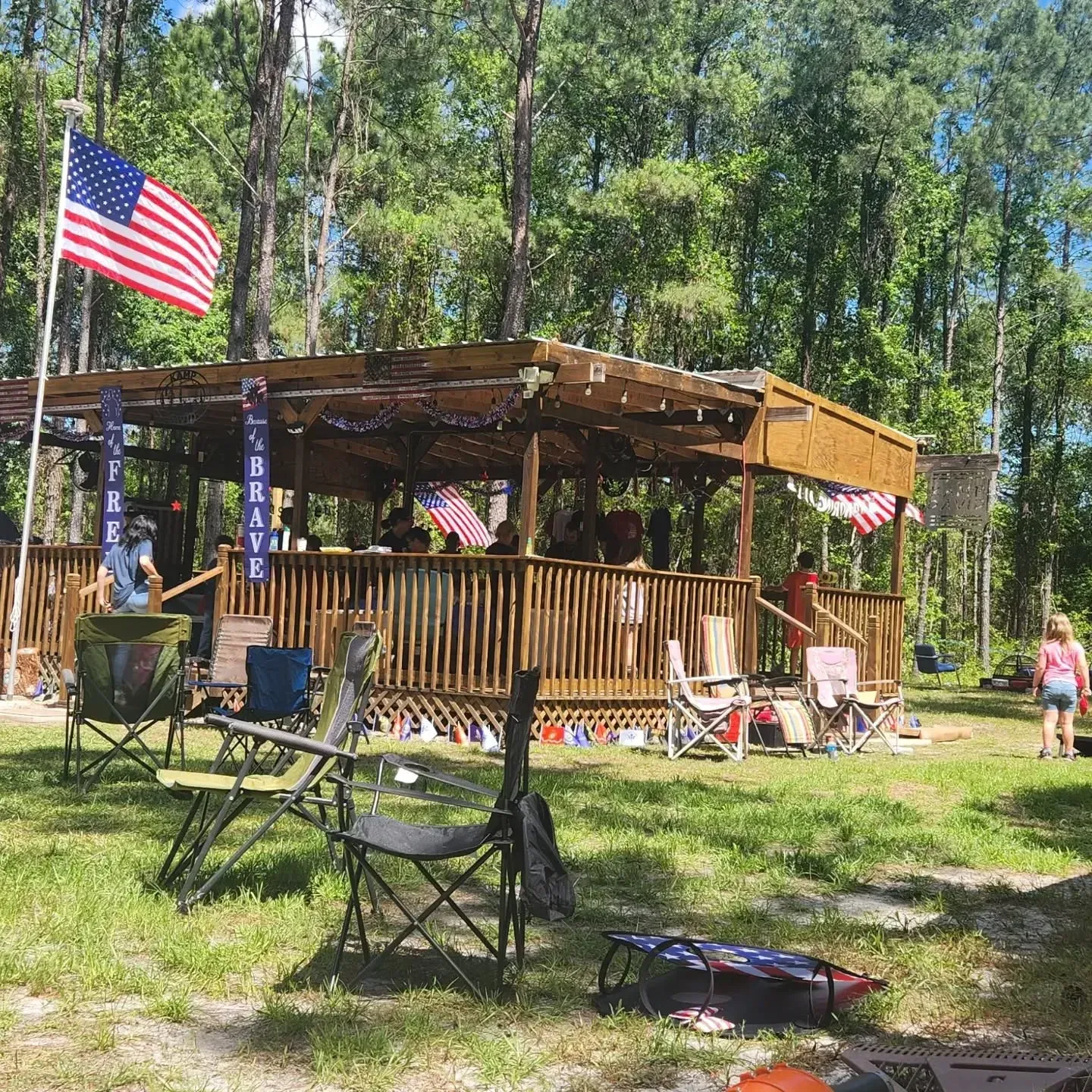 A group of people are sitting in chairs in front of a pavilion.