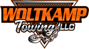 Orange and black logo for Woltkamp Towing LLC, featuring a triangular background, metallic text, and a towing chain hook.