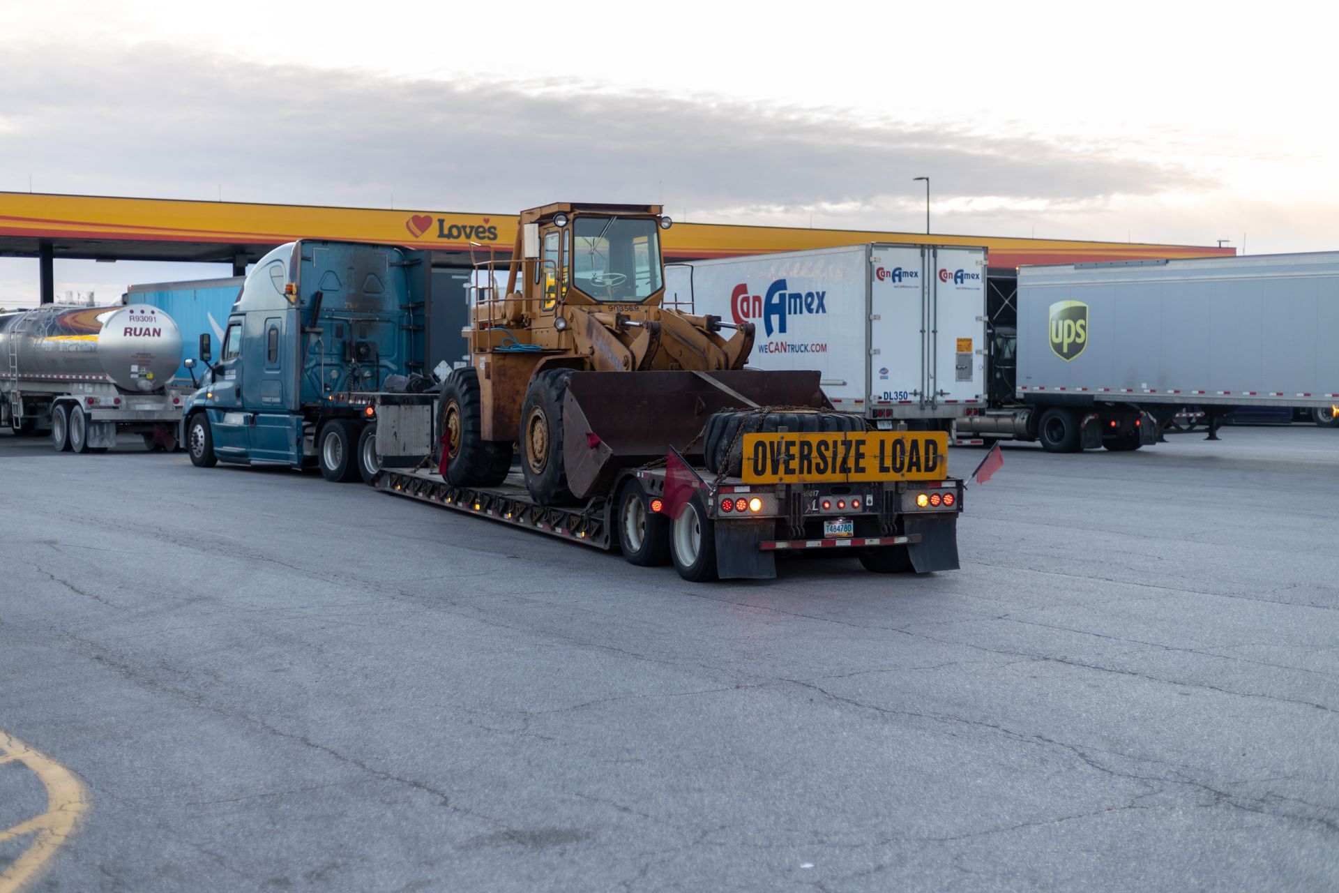 A flatbed truck carrying a large yellow construction loader with an 