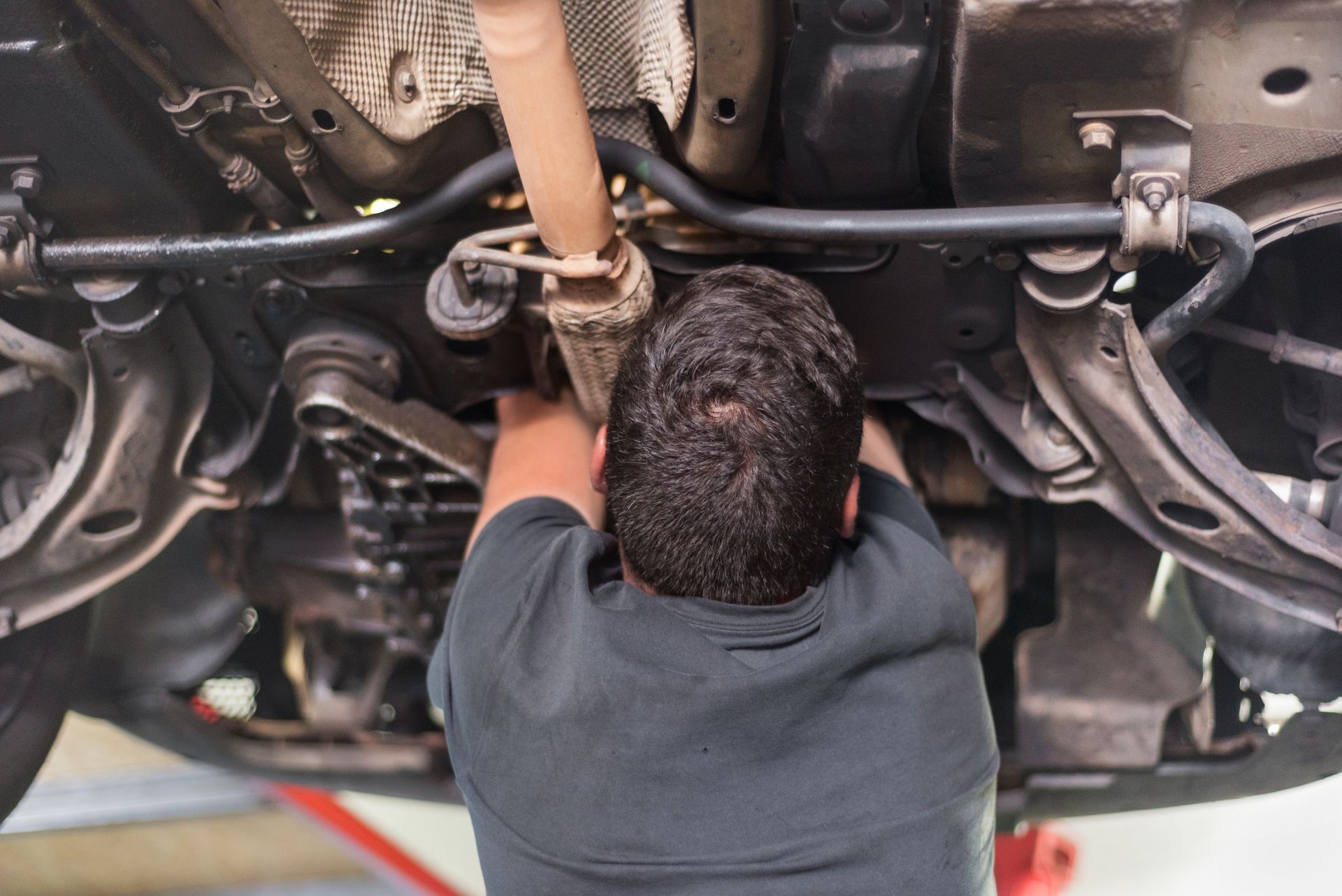 A man is working underneath a car in a garage.