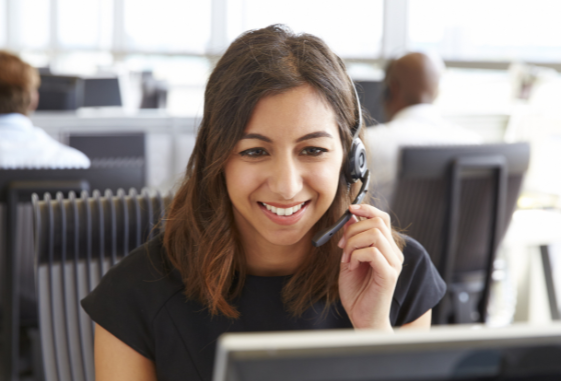 A woman is wearing a headset while sitting in front of a computer.