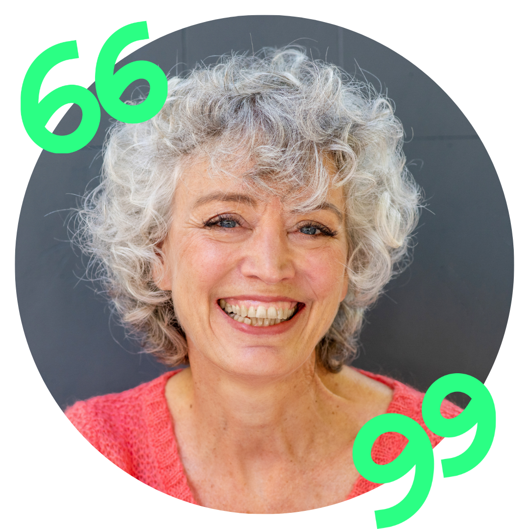 A woman with curly hair is smiling and wearing a red shirt.