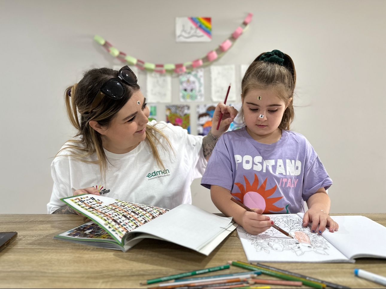 A youth worker pictured with a child doing colouring-in