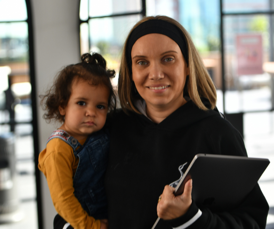 A woman is holding a little girl and holding a tablet