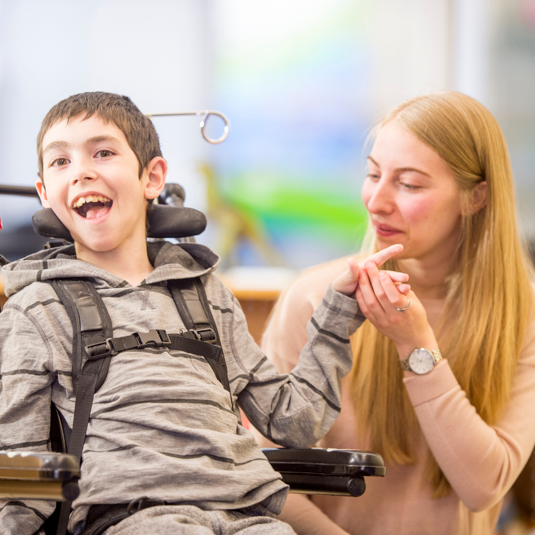 A woman is sitting next to a boy in a wheelchair.