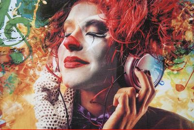 A woman in a clown costume is listening to music with headphones