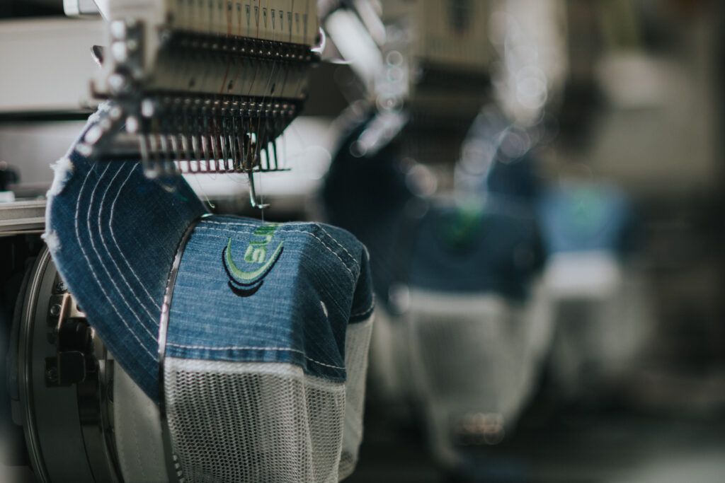 A person is embroidery a hat on a machine in a factory.