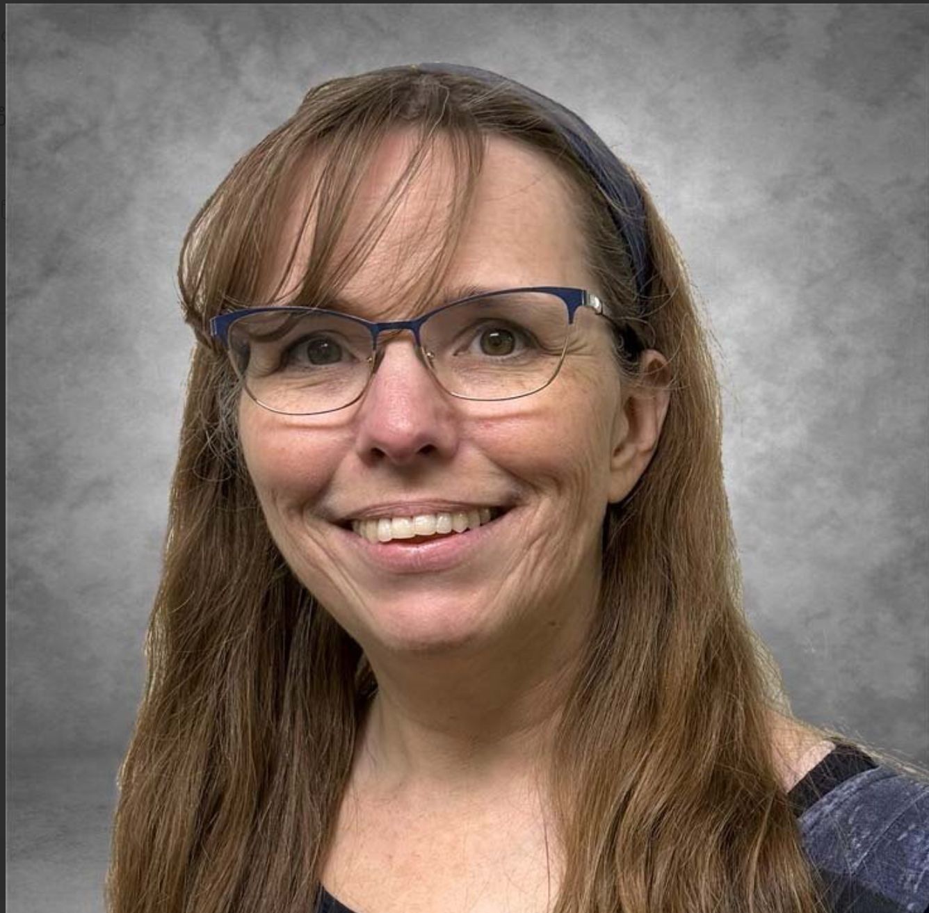 Smiling woman with long brown hair against a gray background