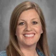 Smiling woman with long light brown hair against a gray background