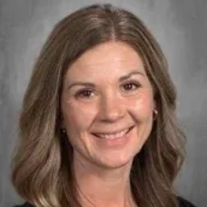 Smiling woman with shoulder-length brown hair against a gray studio background