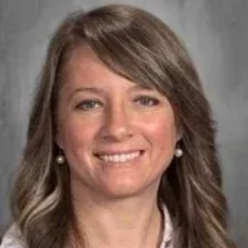Smiling woman with shoulder-length brown hair against a gray studio background