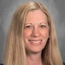 Studio portrait of a smiling woman with long blonde hair against a gray background
