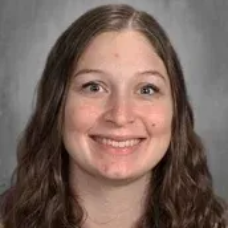 Smiling woman with long brown hair against a gray background