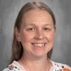 Portrait of a smiling woman with long hair against a gray studio background