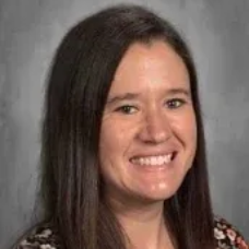 Smiling woman with long dark hair against a gray background