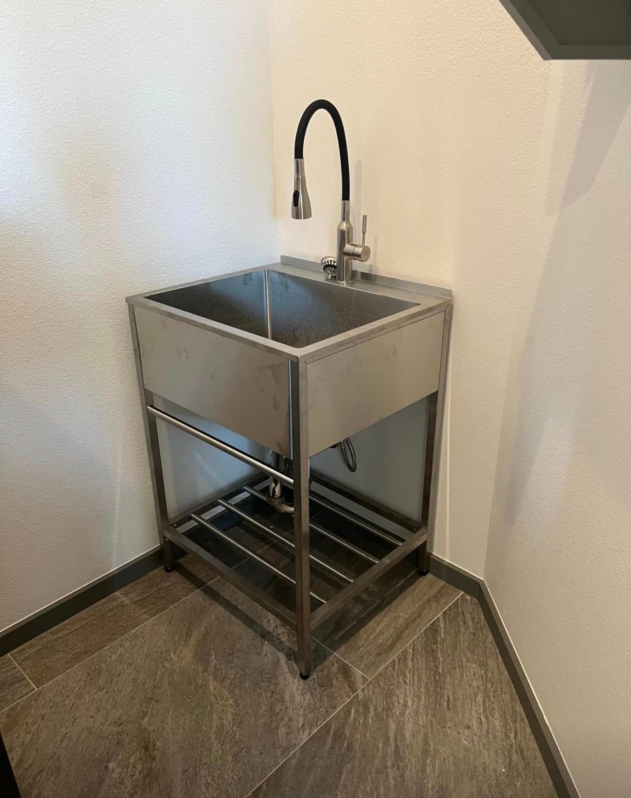 a stainless steel sink with a faucet is in a corner of a room