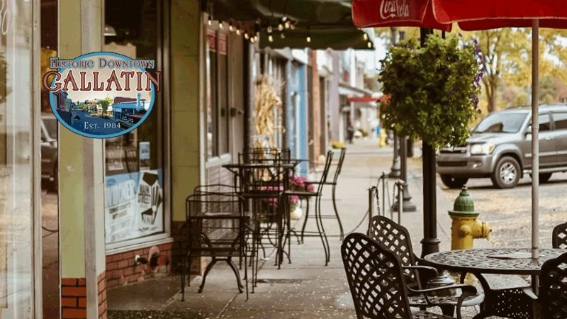 Street view in Gallatin, TN, with shops, outdoor seating, and parked car on a fall day.