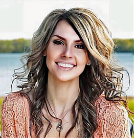 A woman with long hair and a necklace is smiling for the camera.