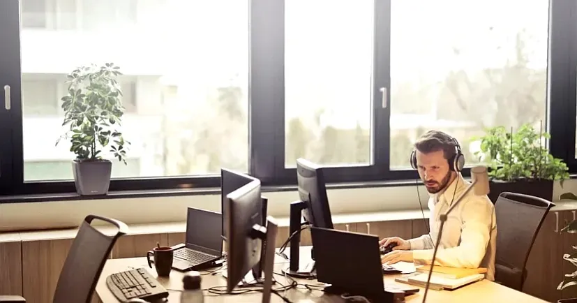 A man wearing headphones is sitting at a desk in front of a computer.