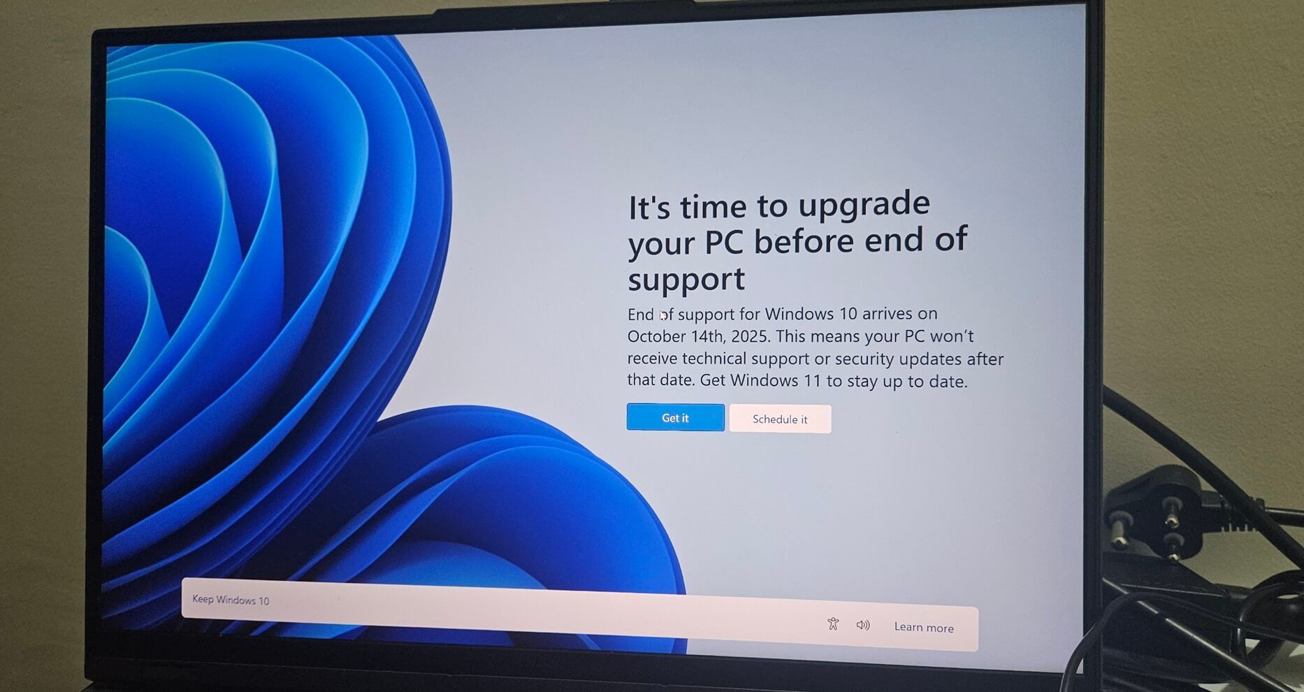 Laptop screen displaying a Windows 11 upgrade notification. Blue and white graphic with