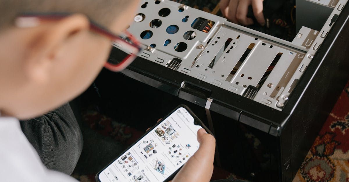 A boy is holding a cell phone in front of a computer case.