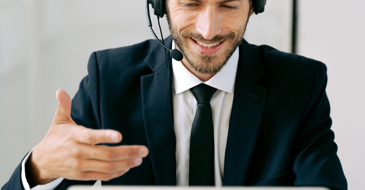 A man in a suit and tie is wearing a headset while using a tablet computer.