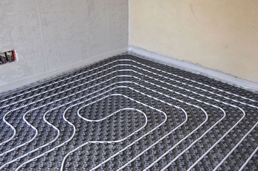 Tubi per il riscaldamento a pavimento radiante posati sul pavimento di una stanza durante la costruzione