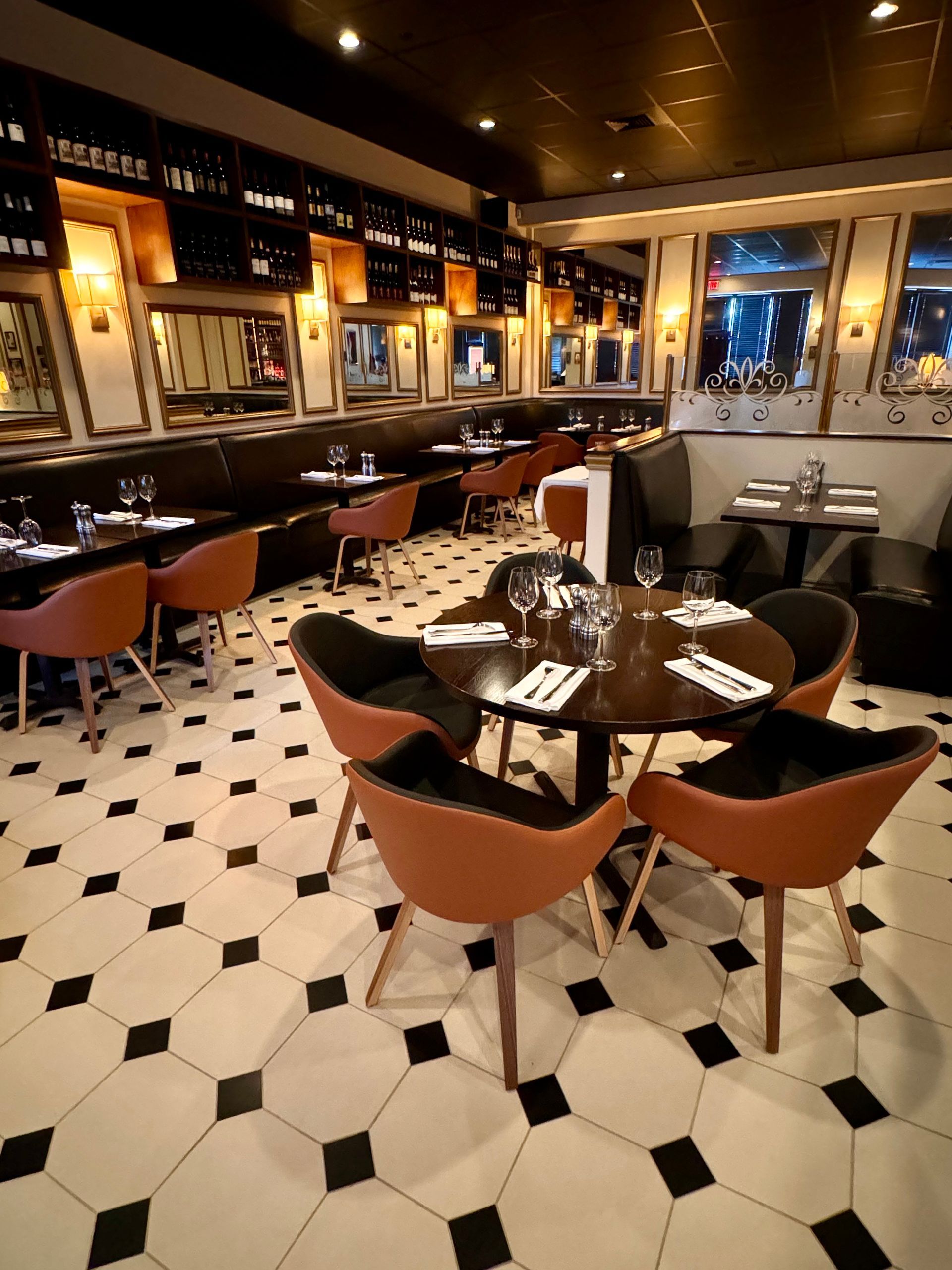 Restaurant interior with brown chairs, black and white tiled floor, and tables set for dining.