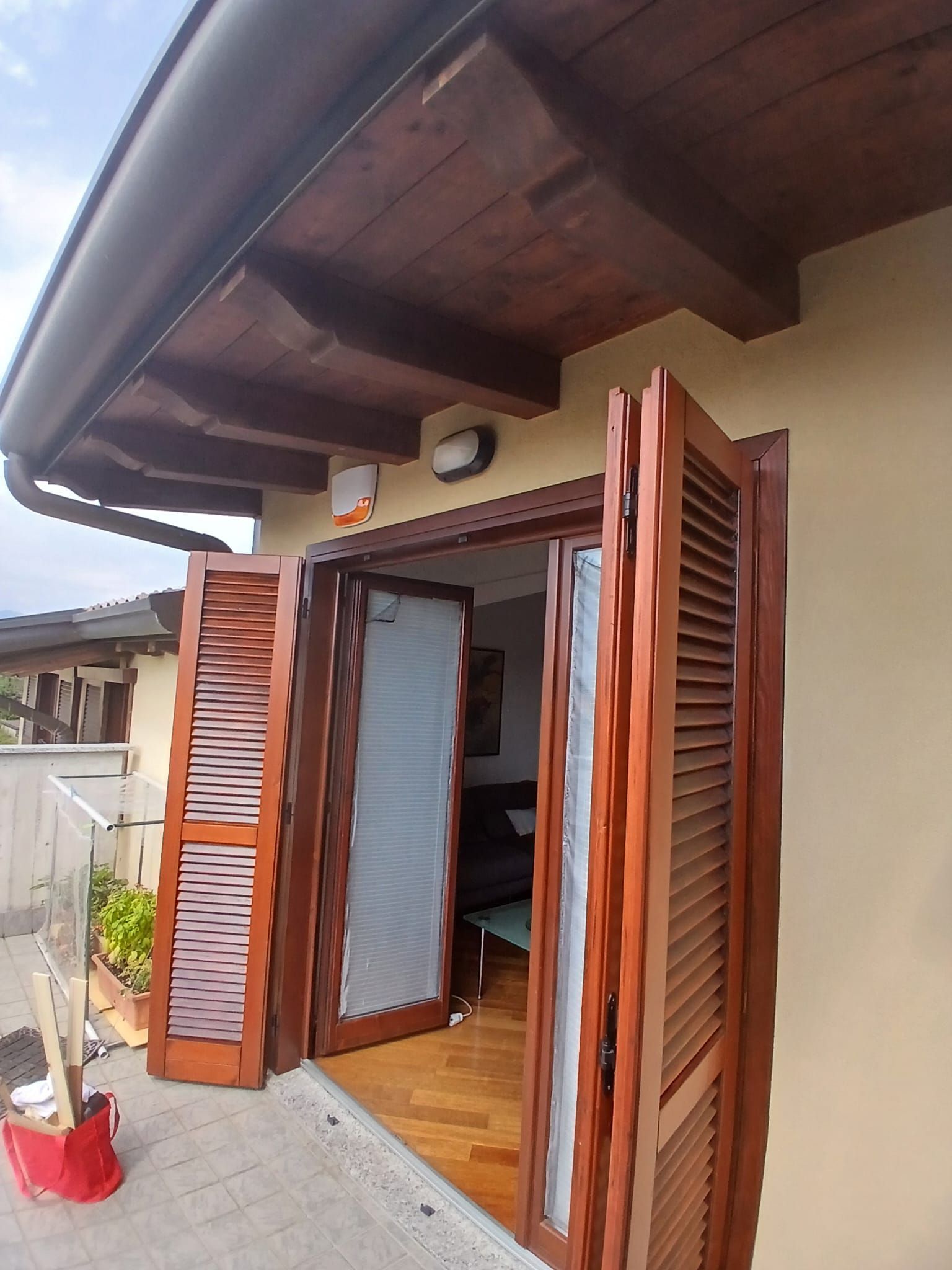 Le persiane in legno si aprono su un balcone con vista interna.