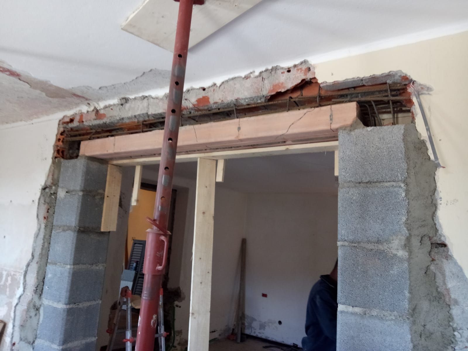 Ristrutturazione: Porta con palo di sostegno, travi a vista e pareti in blocchi di cemento.