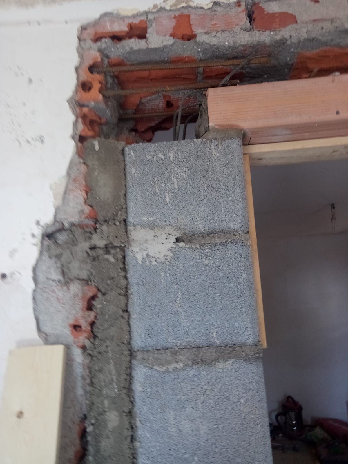 Costruzione di un telaio di porta con blocchi di cemento e mattoni a vista.