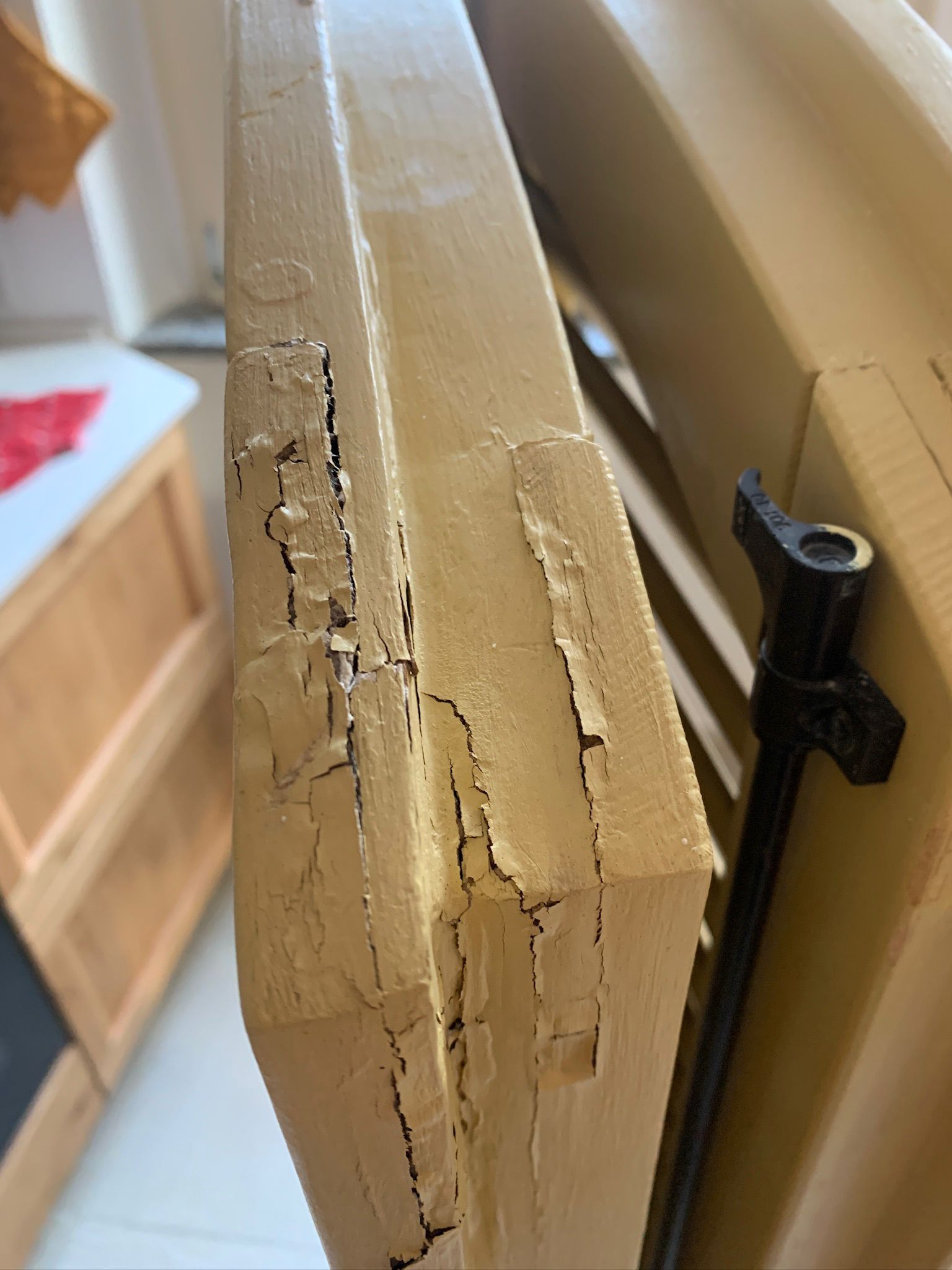 Primo piano di una struttura in legno chiaro danneggiata, con crepe visibili e materiale scrostato.