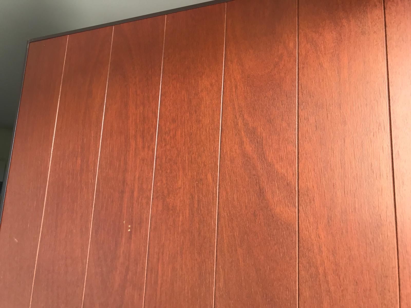 Anta in pannello di legno con assi verticali, colore bruno-rossastro e venature del legno visibili.