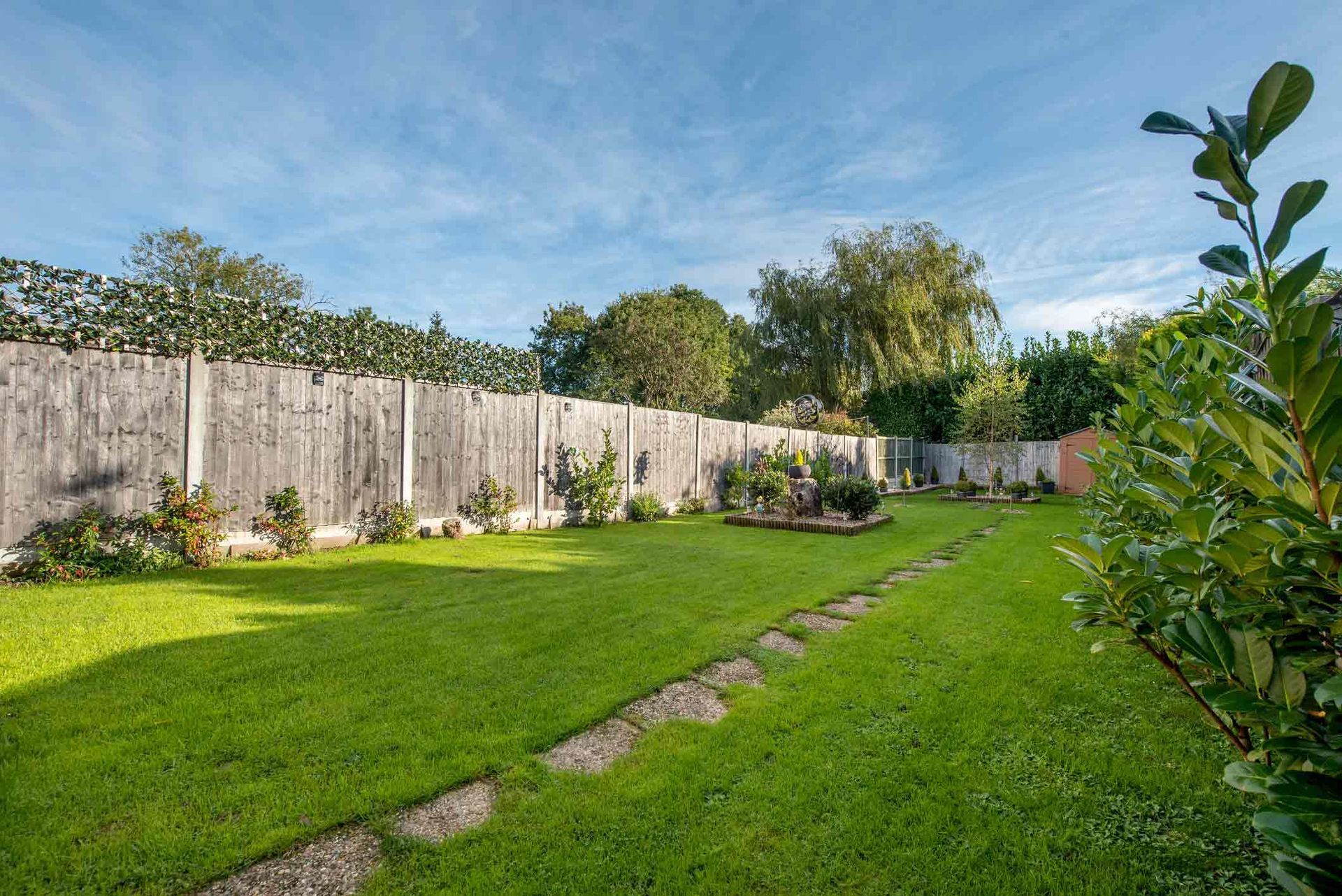 A Lush Green Yard With A Wooden Fence And A Path — Dayton, OH — Sharp Edge Landscaping And Lawncare LLC