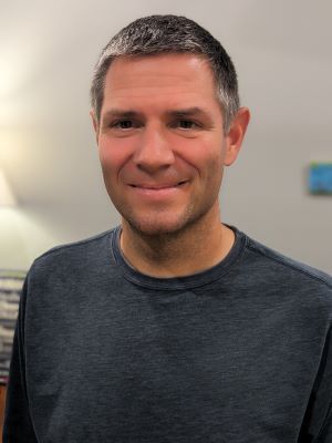 A man in a blue shirt is smiling for the camera.