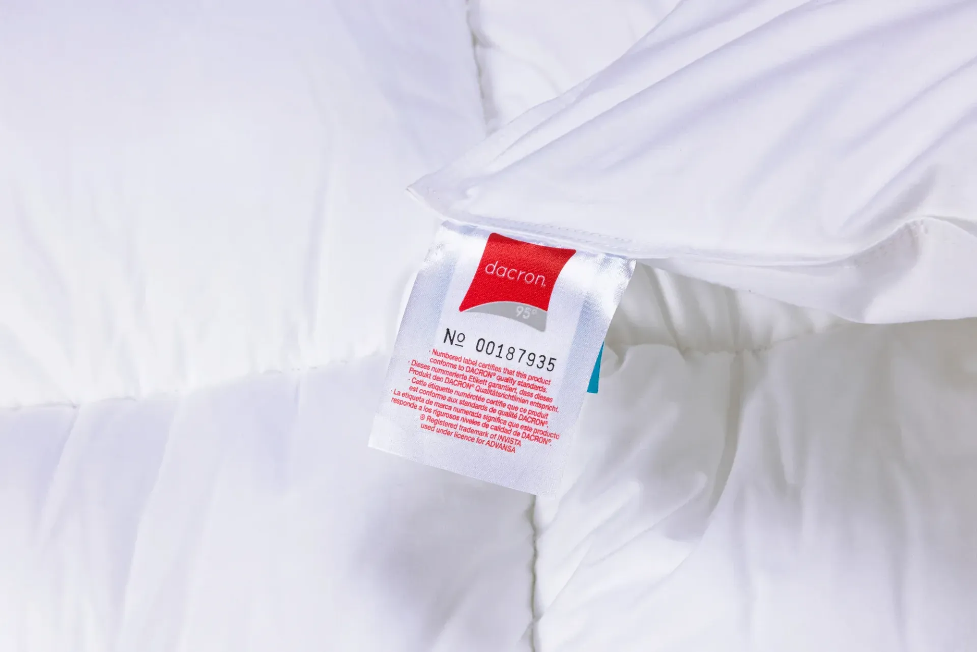 Piumino bianco piegato. Design trapuntato con cuciture a vista.