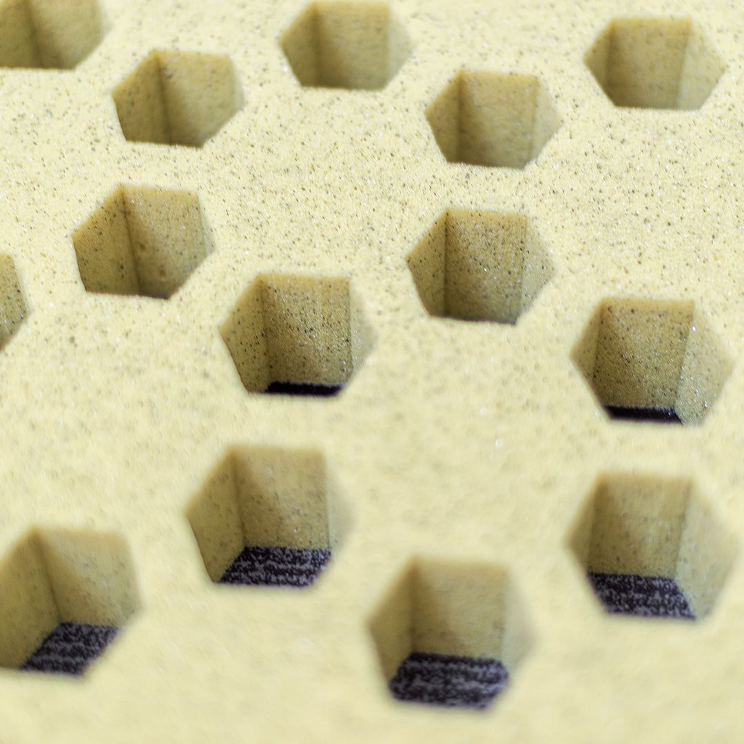 Primo piano di una superficie strutturata con una griglia di rientranze esagonali, probabilmente schiuma.