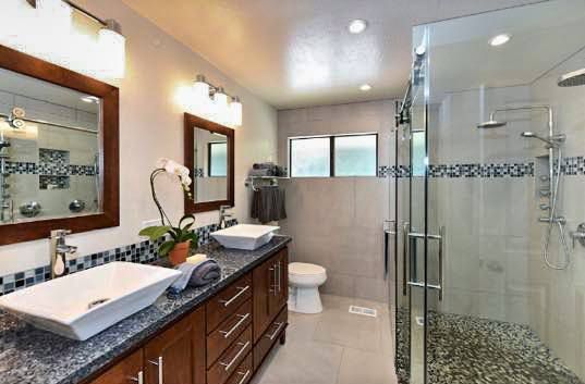 A bathroom with two sinks , a toilet , and a walk in shower.