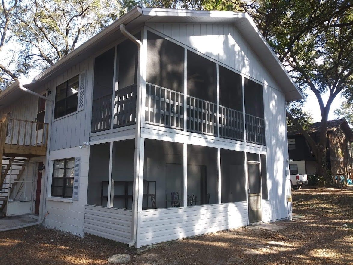 A white house with a screened in porch and balcony