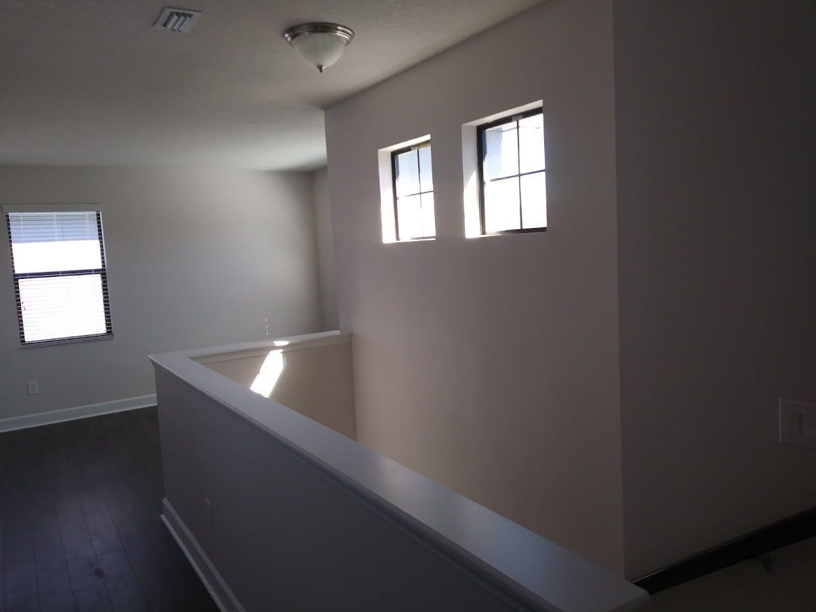 An empty room with a staircase and two windows