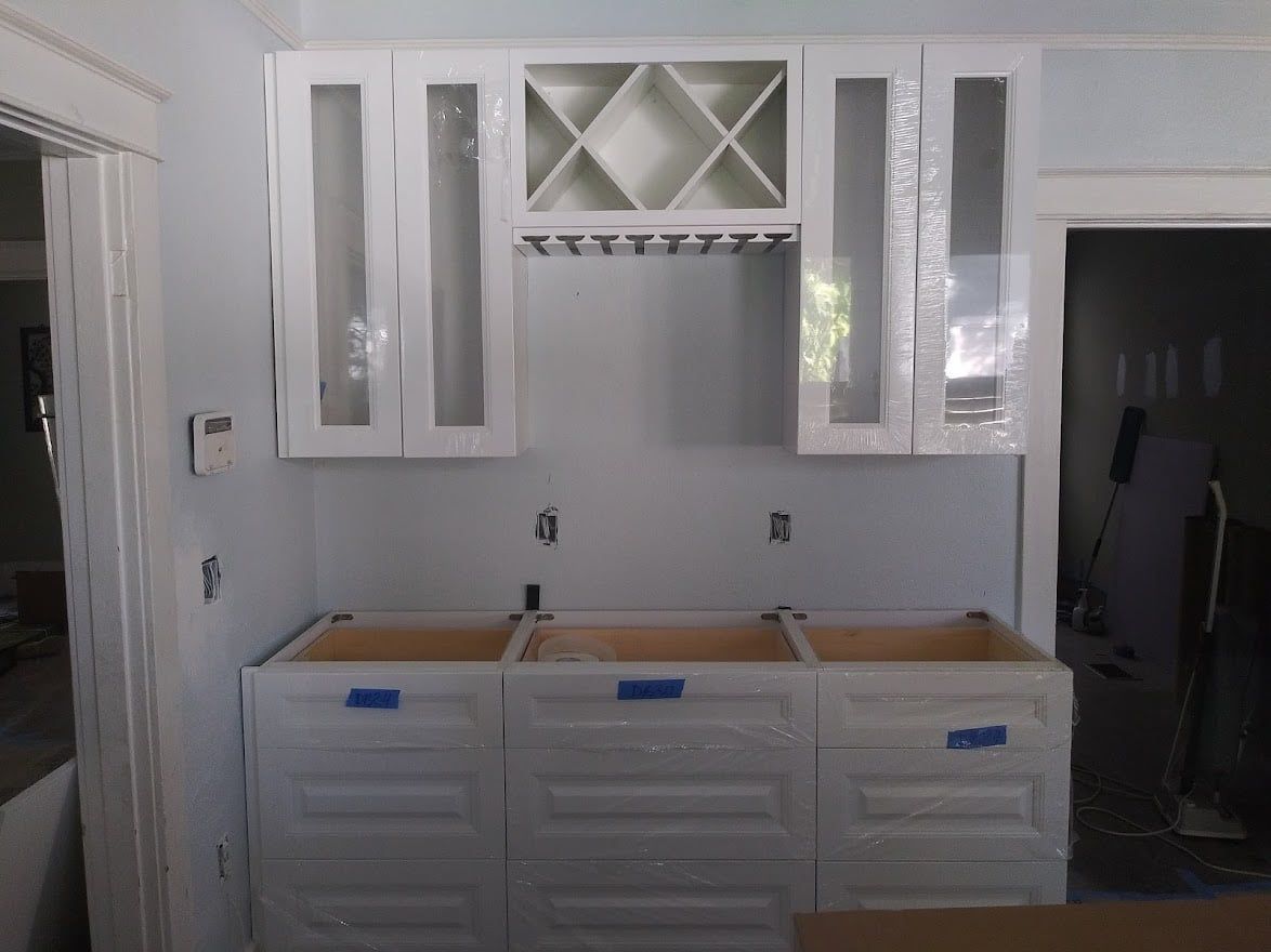 A kitchen with white cabinets and a wine rack
