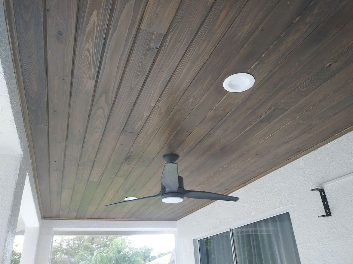 A ceiling fan is hanging from the ceiling of a porch.